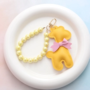 Porte-clés girafe en cuir jaune avec perles nacrées et nœud rose sur assiette céramique