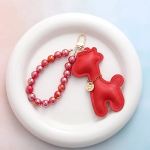 Détail d'un pendentif cerf en cuir rouge avec perles colorées et médaille Lucky Girl