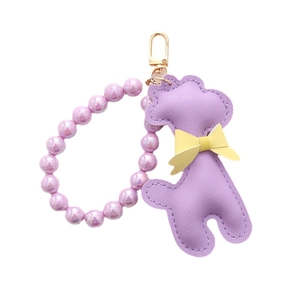 Porte-clés caniche en cuir violet avec perles irisées et fermoir mousqueton doré sur fond blanc