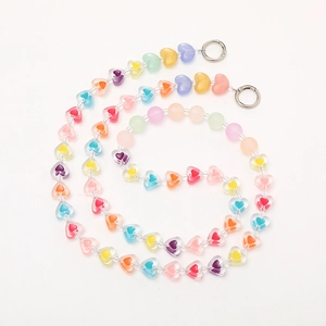 Close-up of macaron heart acrylic beads with metallic spring ring clasps on white background