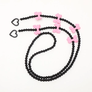 Detailed view of beaded phone strap with pink bows and black heart-shaped spring hooks
