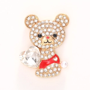 Détail d'une broche en forme d'ours avec strass brillants et un grand cristal de cœur rouge