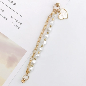 Irregular pearl and gold link chain bracelet featuring a white heart charm pendant