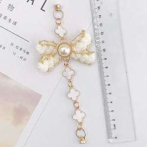 Detail of white knit bow charm with pearl inlay and clover chain measuring 15cm length