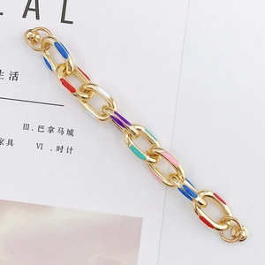 Dettaglio di ciondoli in smalto colorato su una catena a maglie dorate per accessori fai-da-te