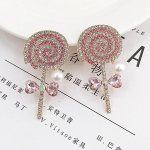 Pink rhinestone lollipop earrings with heart crystal bow and pearl detail on white tray