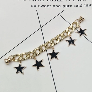 Golden chain bracelet with black star charms and magnetic clasp on decorative card