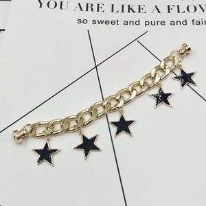 Detail of a chunky gold chain with black star pendants and a magnetic clasp closure