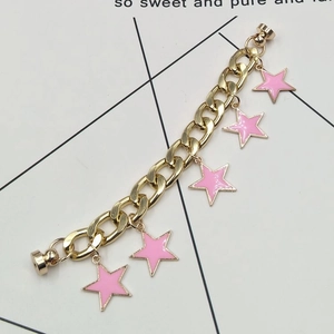 Detailed macro view of a gold Cuban chain featuring pink star pendants and magnetic clasps