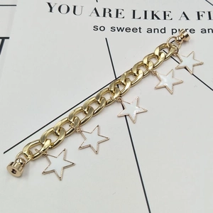 Macro detail of a gold Cuban chain with white star charms and magnetic clasp closures