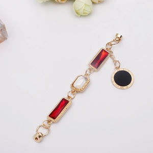 Golden DIY bracelet chain with red gemstone charms and Roman numeral pendant detail