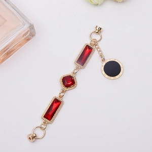 Golden chain jewelry with red gemstones and Roman numeral pendant on white background