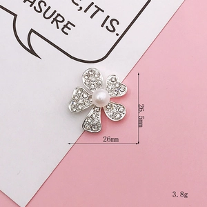 Detailed view of five-petal flower charm with white rhinestones and pearl center