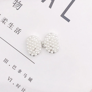 Close-up of DIY acrylic bow charm with white pearls and rhinestones for winter shoes