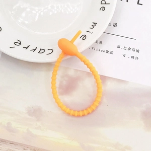 Macro shot of bright orange adjustable silicone cable tie with textured ridges for storage
