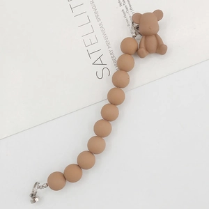 Detail of khaki silicone bead chain featuring a cute matte bear pendant on white background