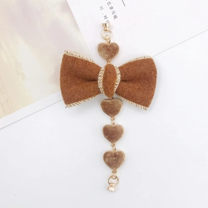 Close-up of brown plush bow charm with golden chain and dangling soft plush heart pendants