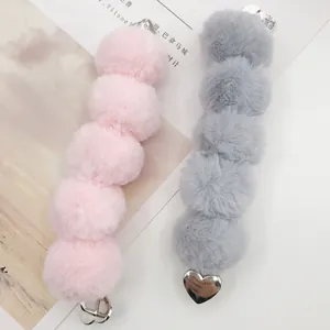 Pink and grey faux rabbit fur pom pom phone chain with heart-shaped adhesive metal clips