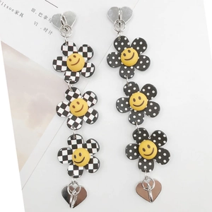 Gros plan sur des boucles d'oreilles fleurs avec motifs à carreaux et breloques smiley