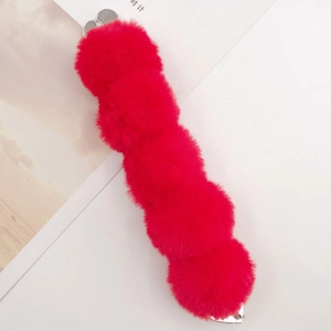 Detail of five vibrant red faux fur pom-poms on a metallic silver alligator hair clip