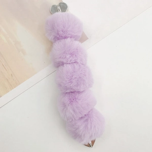 Close-up of five lavender faux fur pom-poms with a silver heart clip for DIY accessories