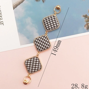 Elegant houndstooth square charm accessory with gold woven edges and metal chain details