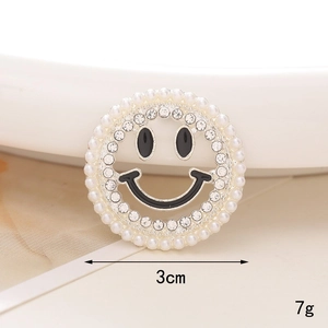 Macro shot of a 3cm silver alloy smiley face charm with pearls and clear rhinestones