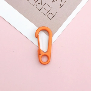 Detail of a bright orange lobster clasp with spring gate mechanism on a pink background