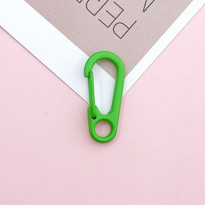 Detailed view of a lime green lobster clasp with spring closure on a pink background