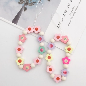 Detail view of two pastel flower beaded phone charms with macaron colors and wooden beads
