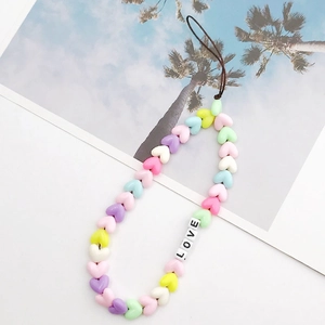 Macro shot of colorful heart-shaped macaron beads and white LOVE letter beads on a phone strap