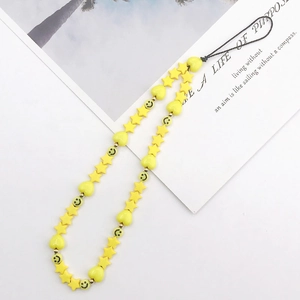 Macro shot of yellow beaded phone strap featuring stars, hearts, and smiley faces