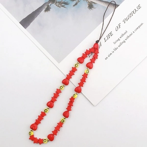 Detail of red star and heart beads with a yellow smiley face on a handmade phone charm