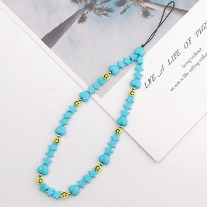 Detail view of blue and yellow beaded phone strap with star, heart and smiley charms