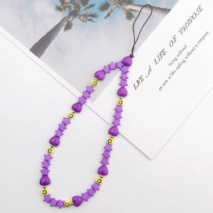 Detail of a Y2K phone strap with purple stars, hearts and yellow smiley face beads