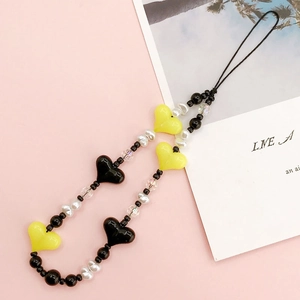 Detail view of handmade beaded phone strap with yellow and black acrylic hearts and pearls
