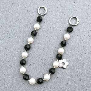 Detail of beaded bag strap with black faceted beads, pearls and silver flower charm