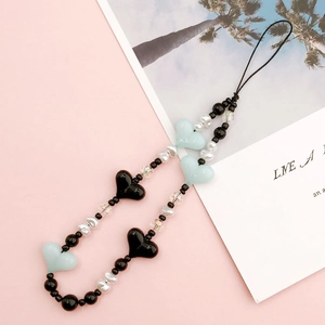 Detail of handmade beaded phone strap with black and blue hearts and faux pearls