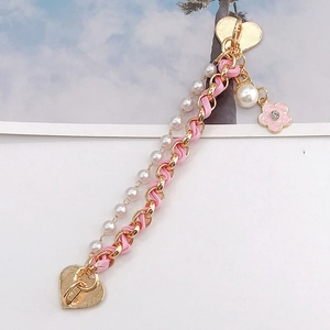 Detail of pink leather woven gold chain with white pearls and heart enamel charms