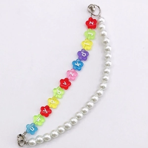 Détail d'un bracelet DIY avec perles de fleurs colorées et fausses perles blanches