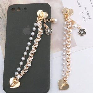 Close-up of pearl and metal chain phone charm with heart buckle and camellia pendant