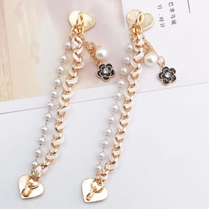Detail of tassel earrings with heart studs, woven leather chains, and camellia pendants