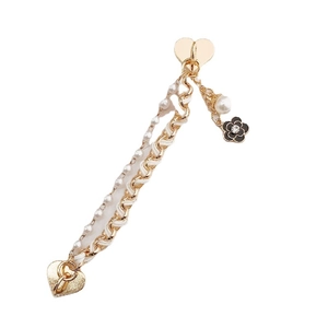 Golden chain and pearl charm accessory featuring a black floral pendant and heart clasp