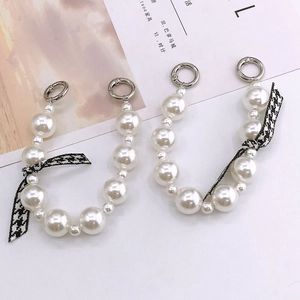 Elegant pearl phone chain with houndstooth bow and silver spring rings on white background