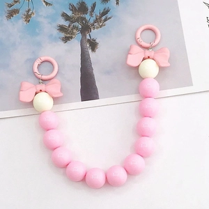 Chaîne de téléphone en acrylique rose avec perles mates, nœuds et mousquetons sur fond blanc