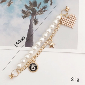 Double-layer pearl and gold chain bracelet featuring a woven heart and star charms