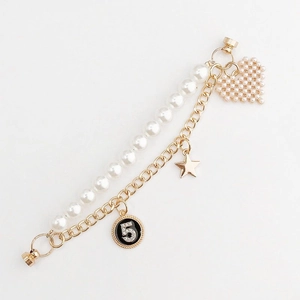 Detail of double-layer bracelet with pearls, golden star and heart-shaped charms