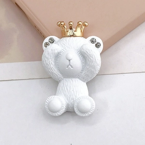 Vue macro d'un charme ours blanc en résine avec couronne dorée et oreilles en strass