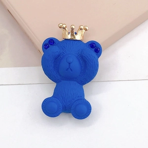 Détail d'une breloque ours bleu avec couronne dorée et oreilles en strass bleus