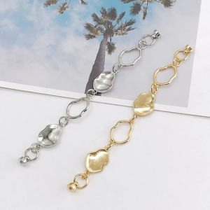 Textured gold and silver wavy link chain with magnetic clasp on a tropical card background